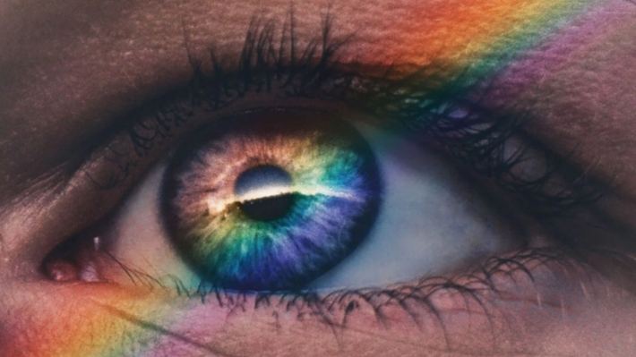 Close-up of an eye with a band of rainbow light across it